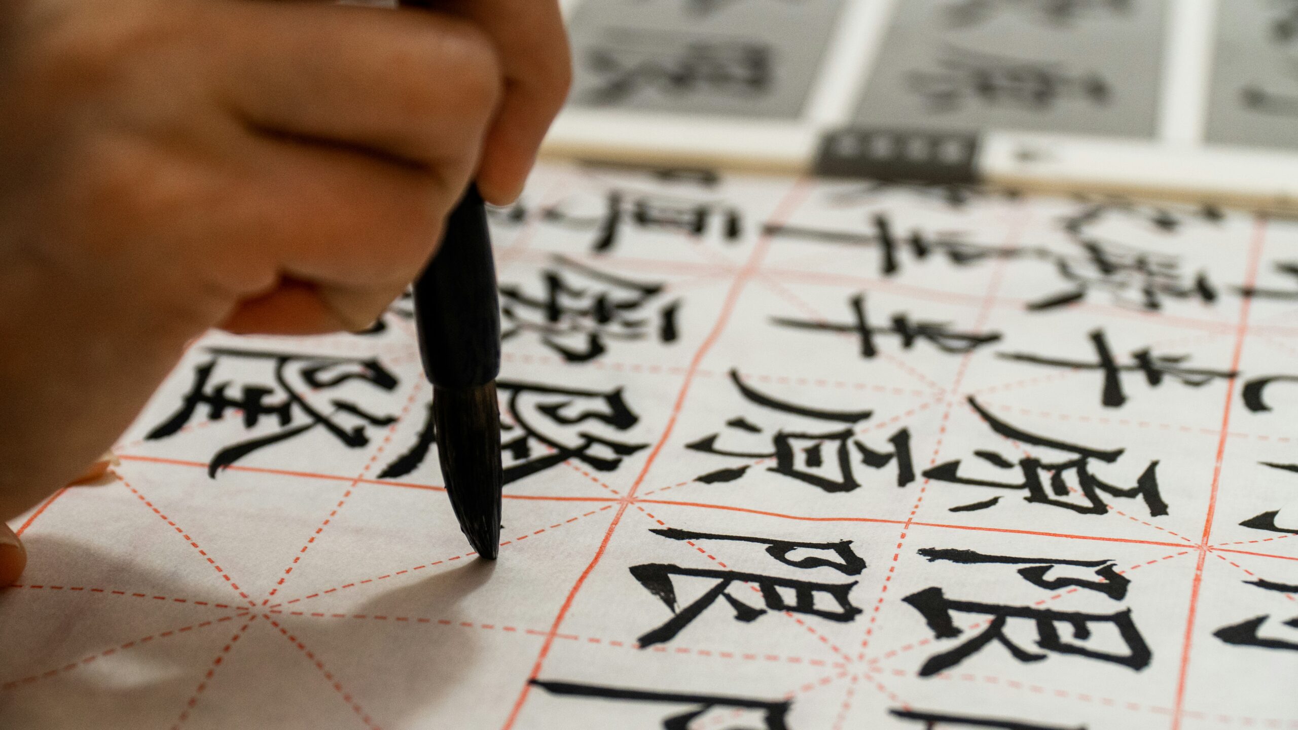 Hand writing Chinese characters with brush on character grid paper.